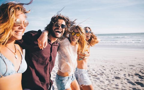 A group of friends with their arms around each other walking on the beach